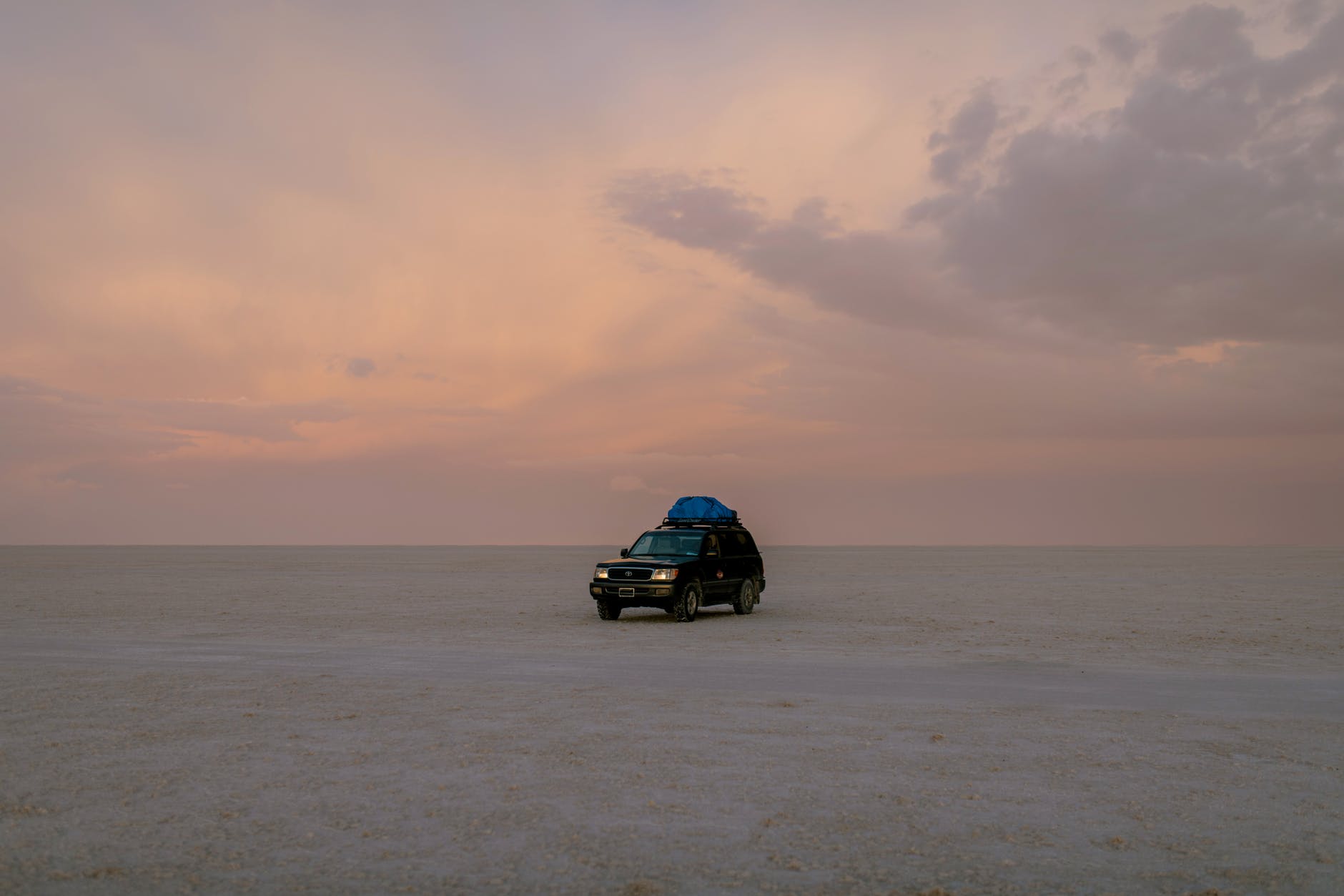 car driving in empty desert in evening